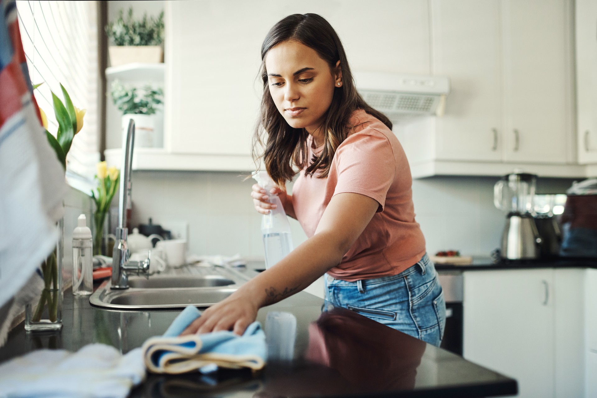 Shot of an attractive young woman using a cloth to clean the kitchen counters at home